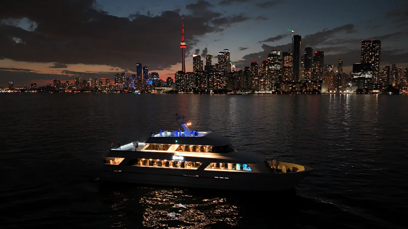 Yankee Lady cruising beside the illuminated Toronto skyline at dusk