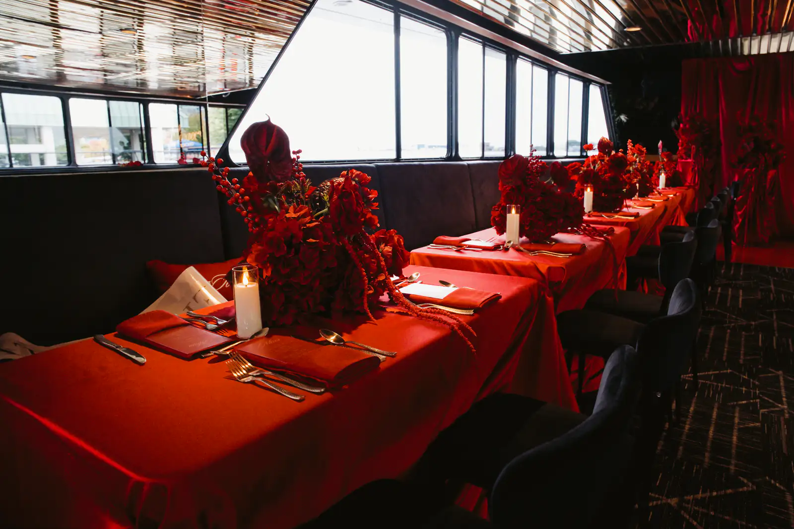Candlelit dining tables with red florals aboard Yankee Lady