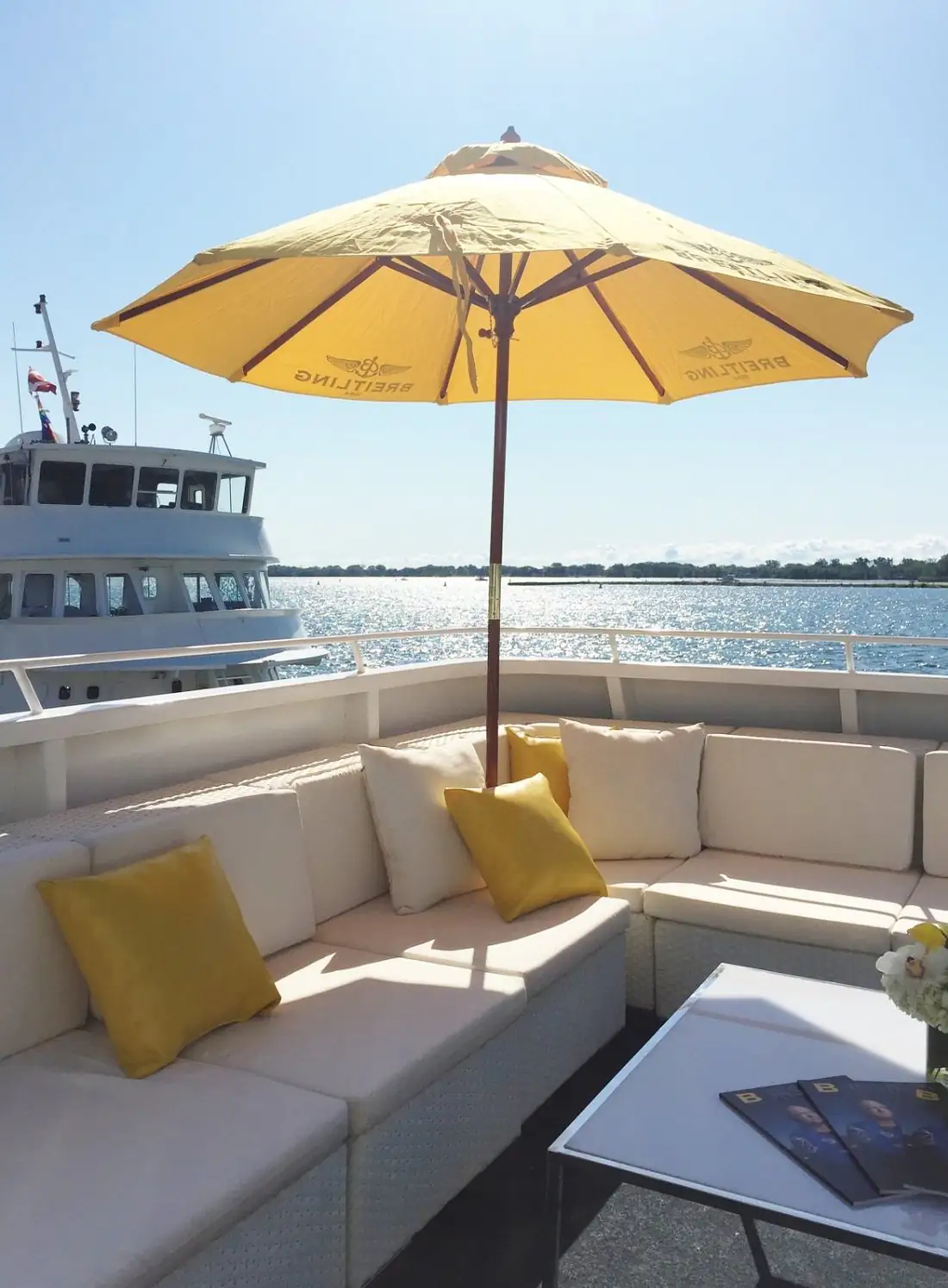 Open-air lounge with a yellow umbrella overlooking the water
