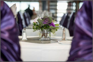 Wedding decor with mauve chair covers and matching floral centrepiece.