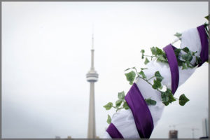 Wedding arch with mauve ribbon and ivy decor and CN Tower in the background.