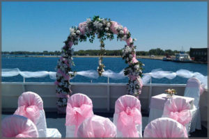 Wedding arch and chairs decorated with pink decor, white flowers and ivy.