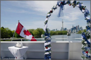 Wedding arch wrapped with blue and white tulle and the Toronto CN Tower in the background.