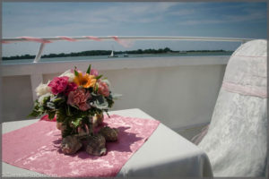 Wedding registration table with centrepiece pink flowers surrounded by sea shells.