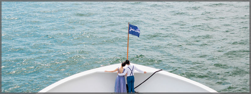 Bride and groom standing on the bow of one of our magnificent wedding cruise ships .