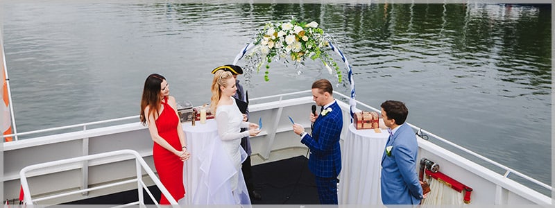 Bride and groom standing on the bow of one of our magnificent wedding cruise ships .